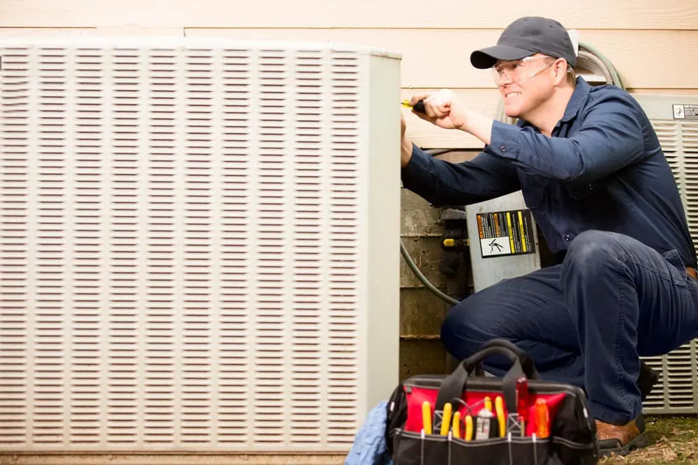 Cam Heating and Cooling | Etowah, NC | repairman working on air conditioning unit outside house
